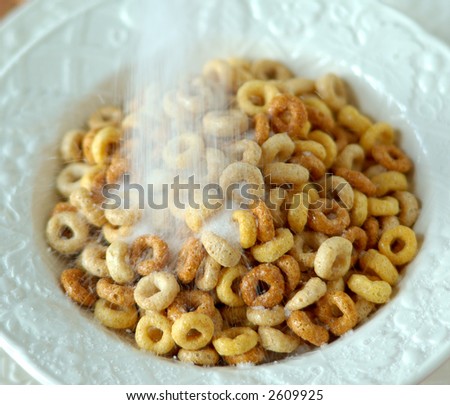 Cereal With Lots of Sugar - Sugar poured on top of multi-grain cereal in a white bowl.