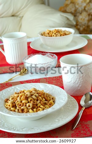 Breakfast of bowls of cereal on a pretty table in the morning. A beautiful breakfast table set with white china bowls of multi-grain cereal sitting on brightly colored red placemats.