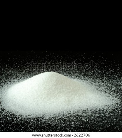 A Mountain of Granulated Sugar on a Black Background - Pure, snowy white mountain of sugar on a black textured background with space for copy.