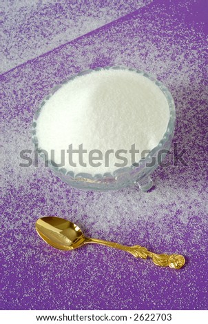 Pure White Granulated Sugar on a Magenta Background - Pure snowy white sugar in a vintage crystal bowl with a gold spoon sitting on a sugar covered magenta textured background.