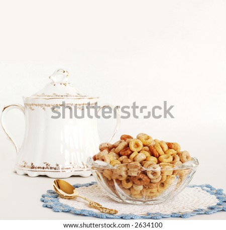 Grandma\'s vintage crystal bowl, sitting on a hand crocheted placemat, holds multi-grain cereal for breakfast. A gold spoon and her vintage sugar urn sit nearby. Isolated on white with space for copy.