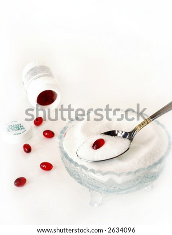 A Spoonful of Sugar Helps the Medicine Go Down - red pills on a spoonful of white granulated sugar over a sugar bowl on a white background.