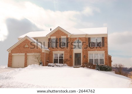 House on a Hill in the Cold of Winter - a two story brick house in the suburbs  on a cold and snowy winter day.