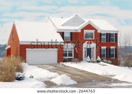House on a Hill in Winter - a suburban brick two story home sitting high on a hill on a beautiful, sunny, winter day.