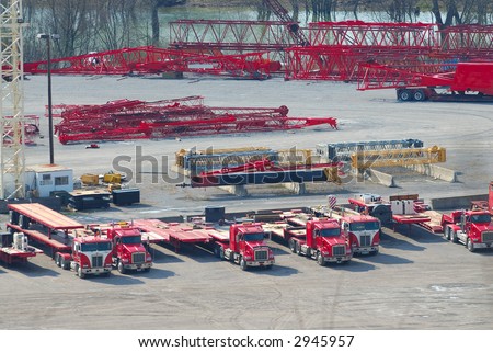Aerial, view of trucks, cranes and lifts at a trucking company near a river.