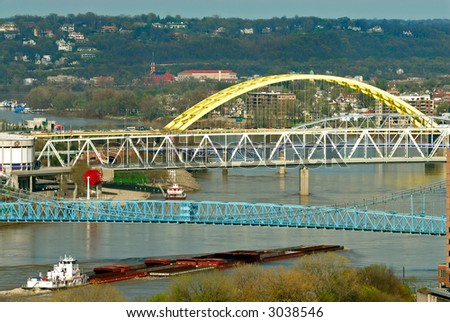 River Barge - A barge pushes up river maneuvering under the many colorful bridges spanning the Ohio River between the cities of Cincinnati Ohio and Covington Kentucky.