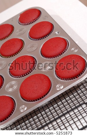 Red Velvet Cupcakes cooling on a rack, fresh from the oven.