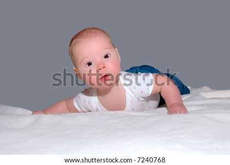 Brown Eyed Baby - A brown eyed baby with a sweet expression at 4 months old lying on his stomach on a blanket.  Learning to hold her head up.