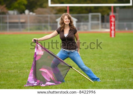 Color Guard Practice - Young woman practicing her color guard routine on a football field.