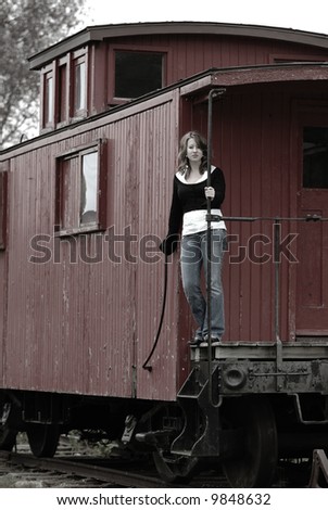 Girl On The Train Caboose standing on the back of an old train car caboose, leaning on the rail.