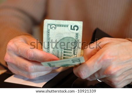 Paying The Bill With Twenty Five Dollars - Male hands holding a five and a twenty dollar bill and the check.  Shallow dof.