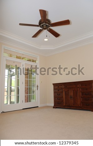 Spacious Empty Room - with only a dresser and a fan in the tray ceiling.  French doors lead to a covered porch.