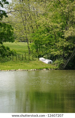 Boat On The Shore In Spring - A Small boat on the shore by a lake in springtime.