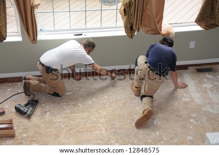 Hardwood Floor Installation - Construction workers installing a hardwood floor over a sub-floor in a residence.