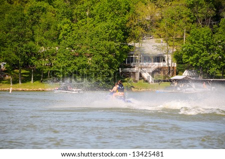 Jet ski sprays water as it speeds around a lake in summer time.
