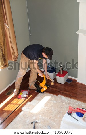Hardwood Floor Installation - Construction worker installing a hardwood floor over OSB sub-floor in a residence.