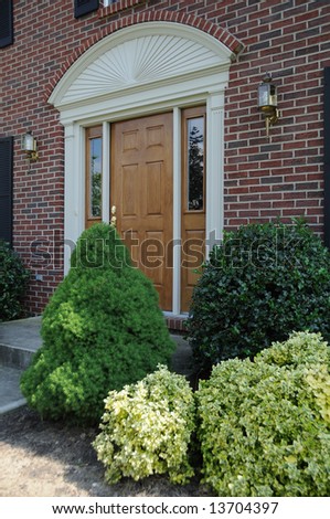 Entry door of a brick suburban home on a sunny summer day.