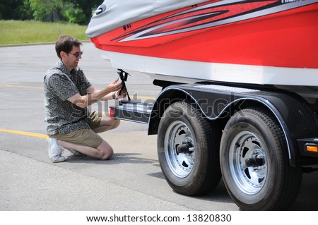 A Man Adjusting Tie Down Straps On Boat Trailer