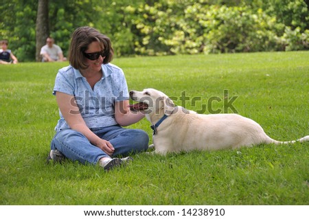 Woman sitting on the lawn petting her dog.