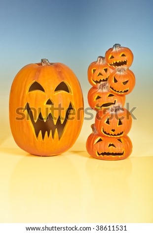 Halloween Jack O Lanterns already carved and sitting on a table.  One large pumpkin and one stack of 6 small pumpkins.