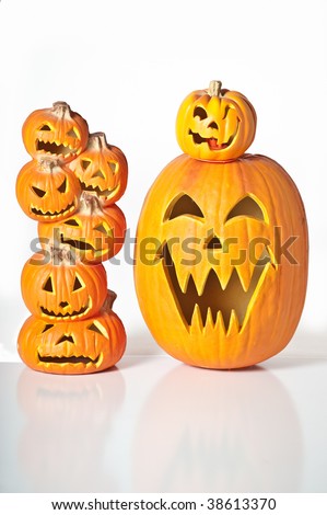 Halloween Jack O Lanterns already carved and sitting on a table.  One large pumpkin and one stack of 6 small pumpkins.