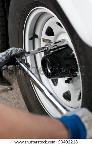 Mechanic using a torque wrench socket and extension on the lug nuts of a truck wheel.