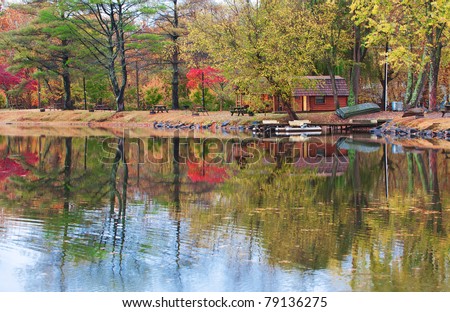 Fall colors of the trees and a cabin reflecting in the water of a small lake in North Carolina, USA.