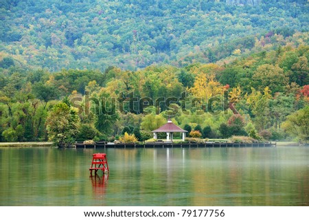 Fall colors of the trees and a gazebo reflecting in the water of a small lake in North Carolina, USA.