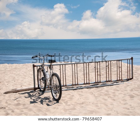 A bike sits in a bike rack on the sand dune along the Atlantic Ocean on a bright sunny summer day.