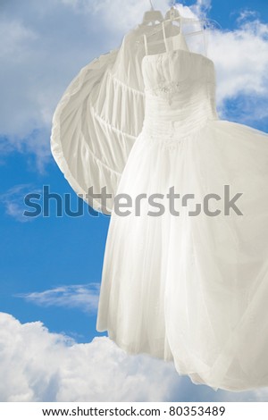  wedding gown is hanging on hangers outdoors against a beautiful blue sky