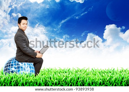Business man on globe and grass field