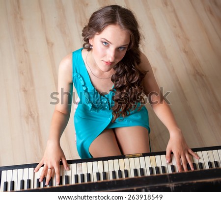 Pianist. Top view of young girl playing piano and looking at camera. Studio shot