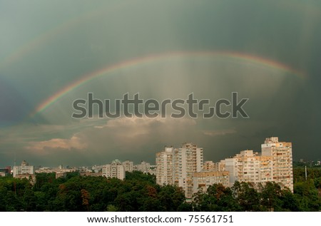 Rainbow over the city. City before/after rain in summer. Rainbow.