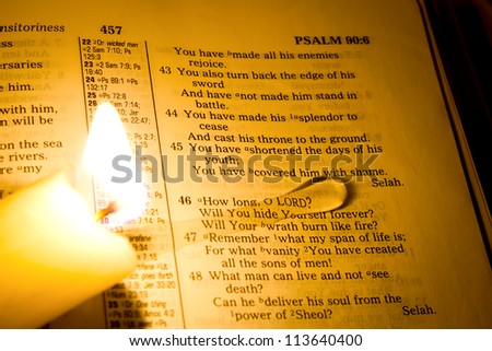 A bible open with a crying candle