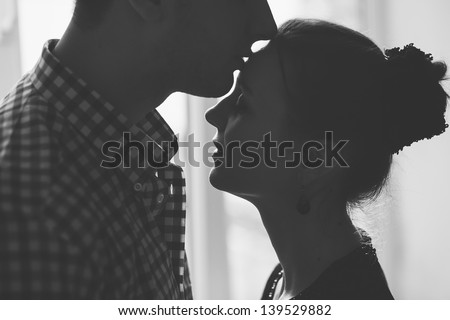 black and white closeup silhouette of woman and man kissing