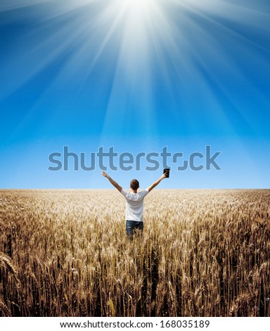 Man Holding Up Bible In A Wheat Field