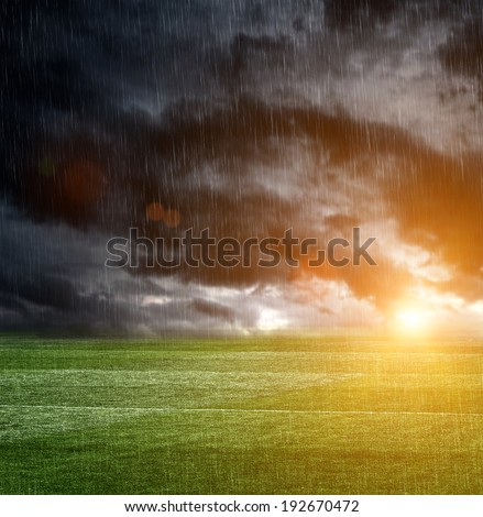 Dark storm clouds over a football field with rain
