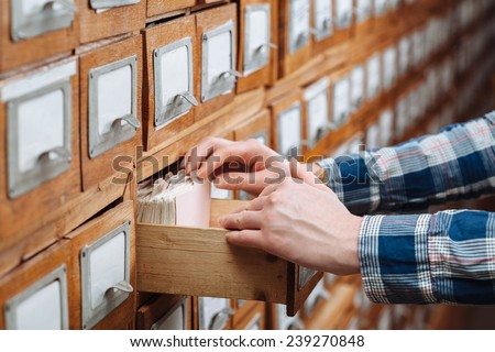 A file cabinet drawer full of files opened by woman hand