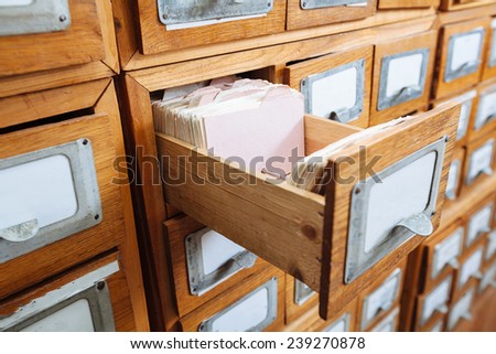 A file cabinet drawer full of files/ wooden shelf