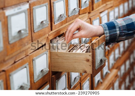 A file cabinet drawer full of files opened by woman hand