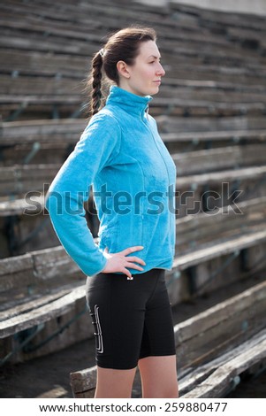 young woman exercises jogging and running on athletic track on stadium on a track and among stadium rows