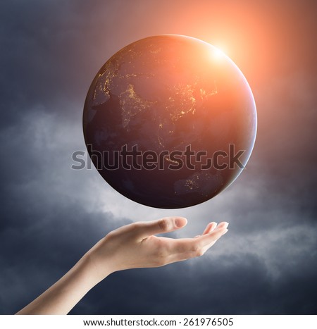 Image of hand holding earth planet on a palm with sun rays spreading around. Female hand is soft and calm. Elements of this image are furnished by NASA
