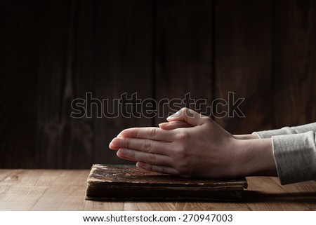 Female hands praying on Bible