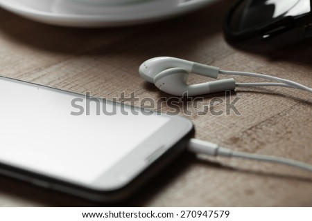 digital music white Headphones among a smart phone and a cup of coffe