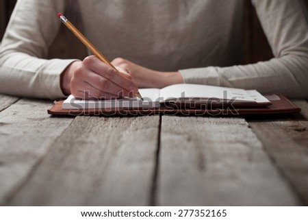 hand writes with a pen in a notebook