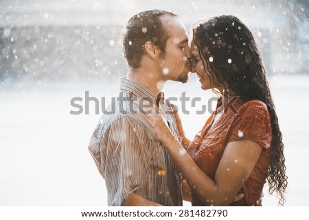 couple in love hugging and kissing under summer rain