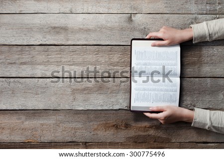 woman hands on bible. she is reading and praying over bible over wooden table