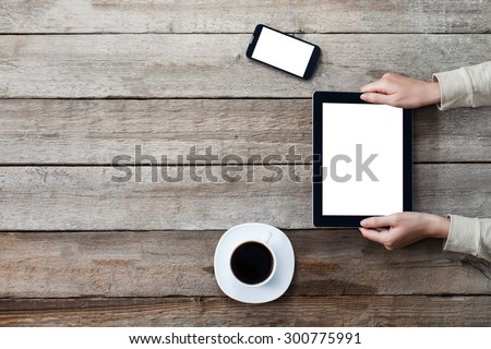 female hands holding digital tablet computer with isolated screen over old grey wooden background table.