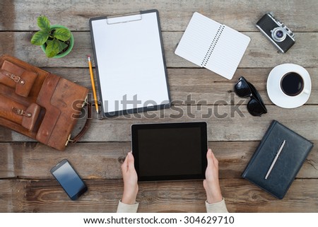 female hands holding digital tablet computer over old grey wooden background table.