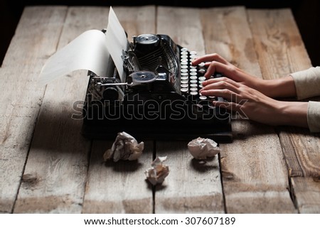 Hands writing on old typewriter over wooden table background